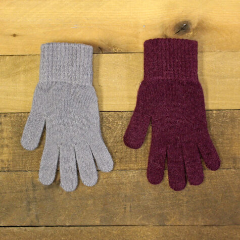 A gray Alpaca glove and a burgundy Alpaca glove on a wood plank.